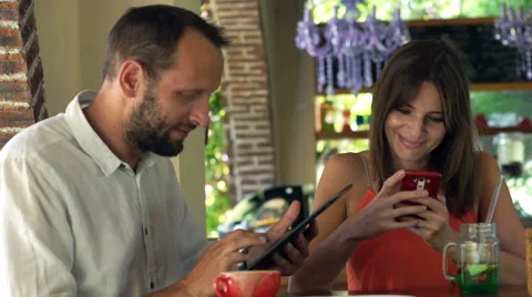 Young couple with tablet and smartphone sitting by table in cafe Stock Footage 68908682