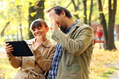Young couple with tablet computer in autumn park waving to friends Stock Footage 8950710
