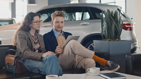 Young Couple with Tablet Computer Choosing New Car in Showroom Stock Footage 246831275