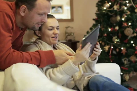 Young couple with tablet computer, Christmas tree in background Stock Footage 10741838
