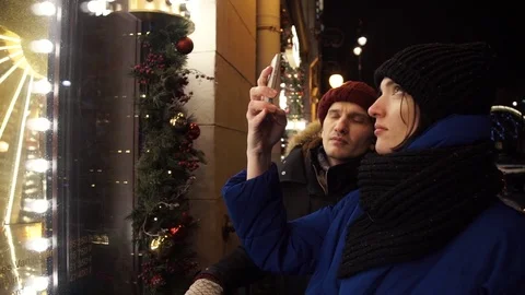 Young couple taking photo using smartphone on a busy urban street in evening Stock Footage 83873708