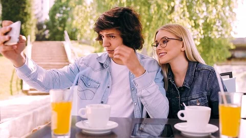 Young couple taking selfie while drinking coffee at cafe's garden Video stock 89825708
