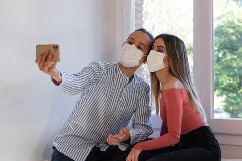 Young couple taking a selfie while wearing a face mask 库存照片