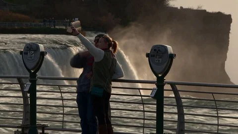 Young couple taking selfies at niagara falls at sunset Stock Footage 84189602