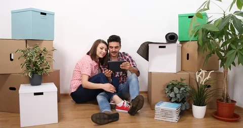 Young Couple Talking About Home Design Use Computer Tablet in New Home Apartment Stock Footage 87909089