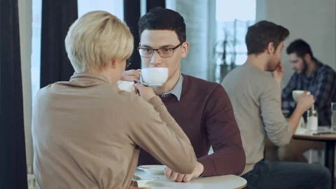 Young couple talking and drinking coffee near the window in cafe Video stock 117223530