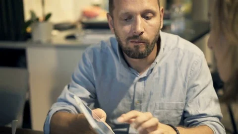 Young couple talking and looking at tablet computer during dinner Stock Footage 80971297