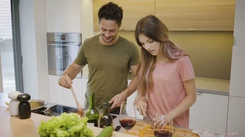 Young couple talking and smiling while cooking dinner in the kitchen Stock Footage 79917400