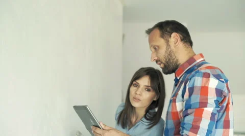 Young couple talking and using tablet during painting their new home Stock-Footage 64582319
