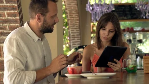 Young couple talking and using modern laptop sitting by counter in cafe Stock Footage