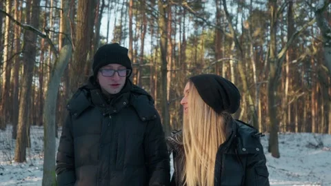 Young couple talking and walking together on a date in a snowy winter forest. 스톡 동영상 311955472