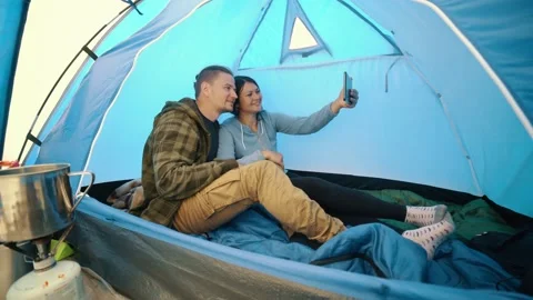 Young couple talking during online video call on tablet in camping tent Stock Footage 202340885