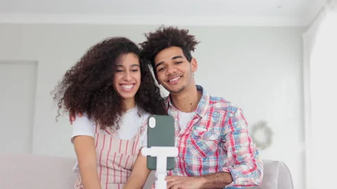 Young couple is talking in front of smartphone and hugging while sitting at home Stock Footage 197397304