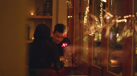 A young couple talking on a romantic dinner date, through the window Stock Footage 51778484