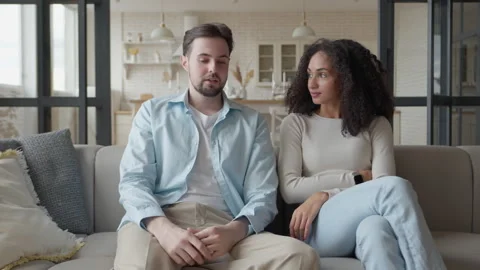 Young Couple Talking Together While Sitting On Sofa At Home Living Room 스톡 동영상 331789194