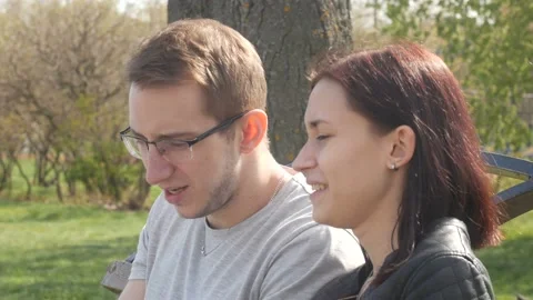 Young couple talking while sitting on the bench on a sunny day 動画素材 90180235