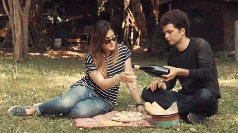 Young couple toasts and drinks in the garden in a sunny day Stock Footage 62978666