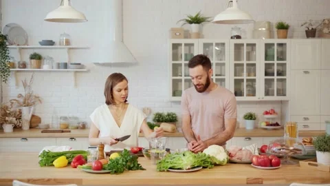 Young couple together preparing dinner chopping vegetables and talking at home Stock Footage 146277152