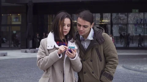 Young couple touching screen of a smartphone together and discussing Stock Footage 74395486