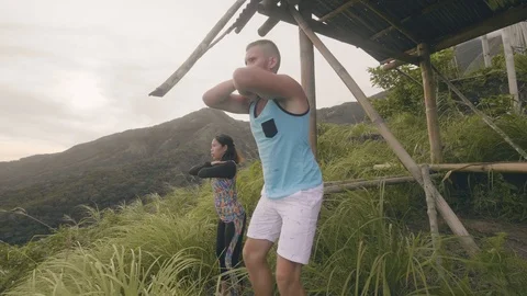 Young couple training squat exercise on green hill landscape. Fitness man and Stock Footage 107138760