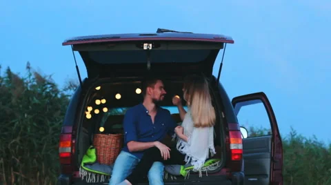 A young couple in the trunk decorated with twinkle lights. Stock Footage 66877931