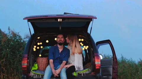 A young couple in the trunk decorated with twinkle lights. Stock Footage 66877936