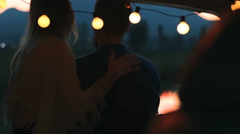 A young couple in the trunk with twinkle lights. Vídeo Stock 66877926