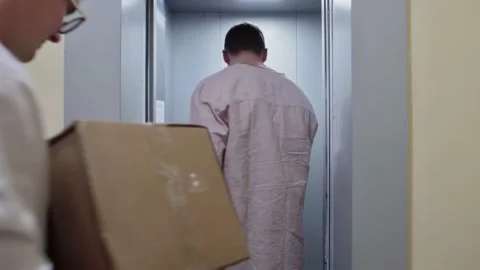 Young couple of two men holds cardboard boxes and enters in the elevator, moving Stock Footage 151312366