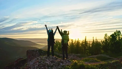 A young couple with two sons happily raise their hands up standing on the top of Stock Footage 159159146