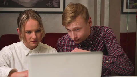 Young couple using and work on laptop, emotionally discussing, doing online Stock Footage 146603713
