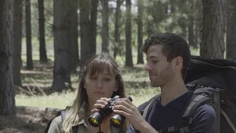 Young couple using binoculars to watch birds in woods Stock Footage 75199292