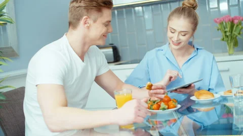 Young couple using digital tablet while having breakfast at home. Stock Footage 86716816