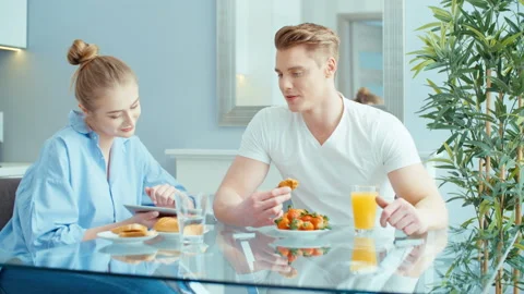Young couple using digital tablet while having breakfast at home. Stock Footage 86717039