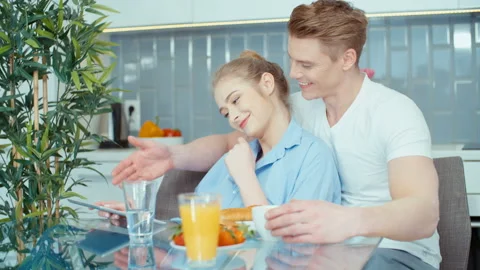 Young couple using digital tablet while having breakfast at kitchen table. Stock Footage 86719281