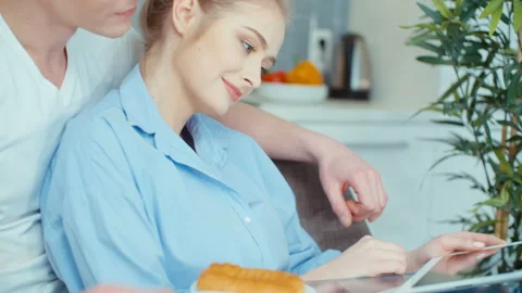 Young couple using digital tablet while having breakfast at kitchen table. 動画素材 86719542