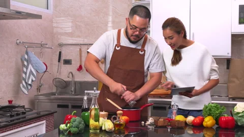 Young couple using digital tablet while preparing a meal. Vídeos de archivo 134408031