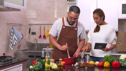 Young couple using digital tablet while preparing a meal. Stock Footage 134413123