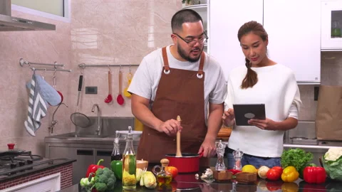 Young couple using digital tablet while preparing a meal. Video stock 134413923