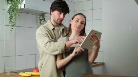 Young couple is using a digital tablet and reading the recipe on culinary Stock Footage 239672123