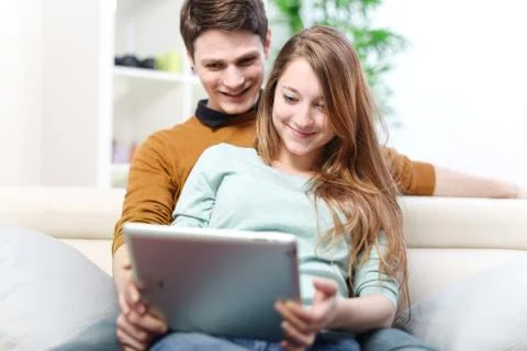 Young couple using digital tablet indoors on the sofa Stock Photos
