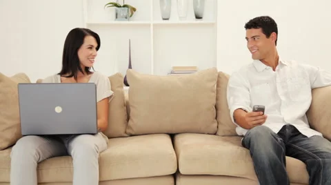 Young Couple using Laptop and Phone while sitting on Couch Stock Footage 912075