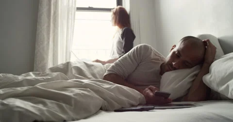 Young couple using laptop and mobile phone in bedroom Vídeo Stock 63374323