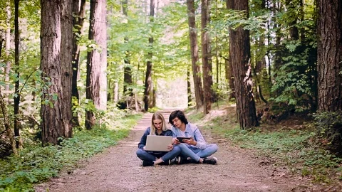 Young Couple Using Laptop And Tablet While Sitting In Forest Video stock 89892112