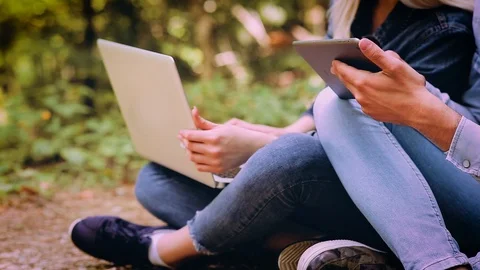 Young Couple Using Laptop And Tablet While Sitting In Forest Video stock 89893022