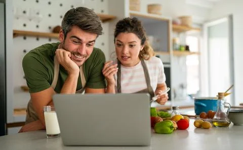 Young couple using laptop computer to take part in online culinary workshop.. Stock Photos