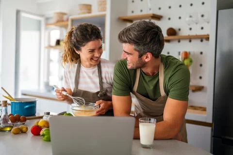 Young couple using laptop computer to take part in online culinary workshop.. Stock Photos