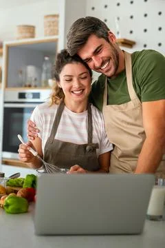 Young couple using laptop computer to take part in online culinary workshop Stock Photos