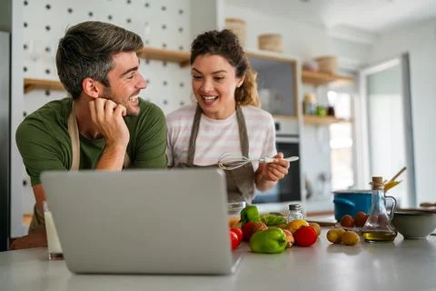Young couple using laptop computer to take part in online culinary workshop Stock Photos