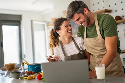Young couple using laptop computer to take part in online culinary workshop.. Stock Photos