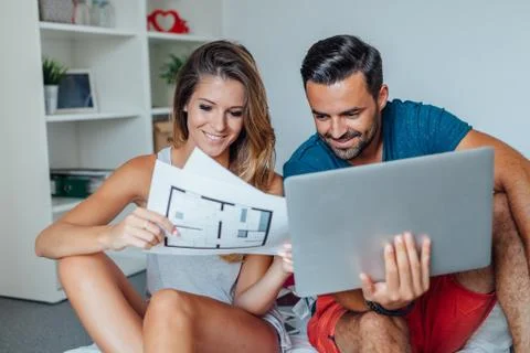 Young couple is using laptop pc while woman is holding architecture plans. Stock-Fotos